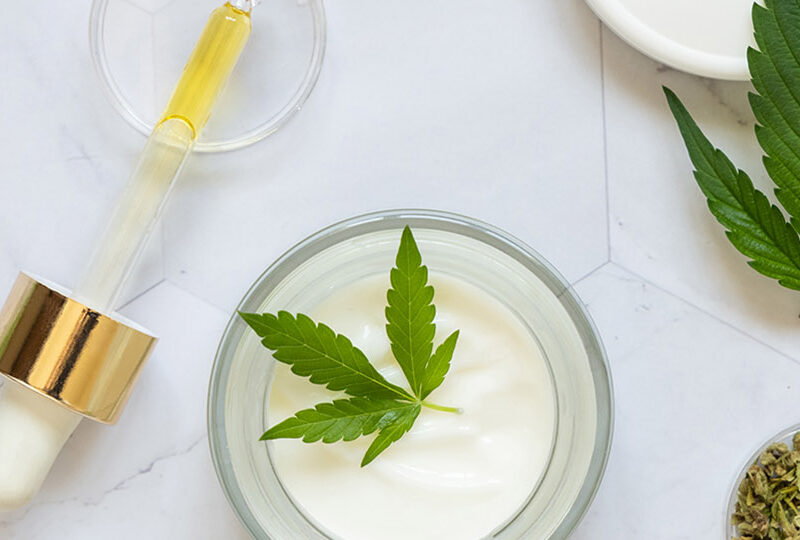 Pipette with CBD oil, cream jar and dry tea near green cannabis Pipette, cream jar and infusion tea near green cannabis leaves top view on marble. Organic healthcare product. Eco friendly CBD oil to relax and sleep. Alternative healthcare and bodycare concept